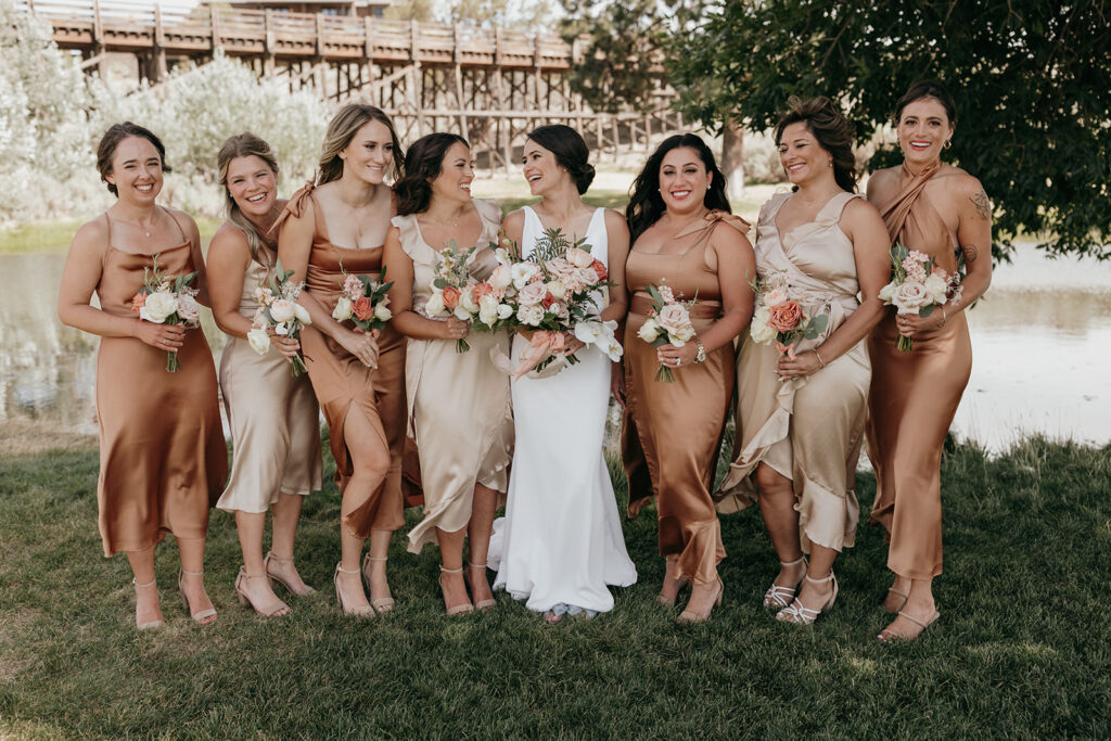 bridal party smiles with bride and holds bouquets